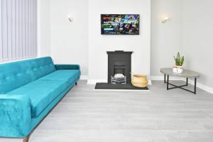 a blue couch in a living room with a fireplace at Heathfield House by YourStays in Crewe