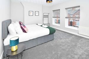 クルーにあるHeathfield House by YourStays - Four Bedroom House in Creweのベッドとテーブルと2つの窓がある寝室