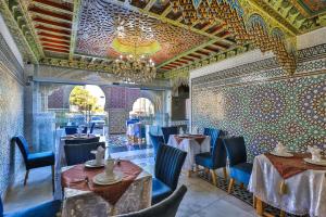 a restaurant with tables and chairs and a chandelier at Hotel & Ryad DALILA in Fez