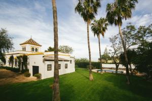 biały budynek z palmami na dziedzińcu w obiekcie Villa La Jara Sanlúcar w mieście Sanlúcar de Barrameda