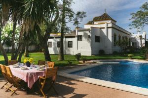 a dining table and chairs in front of a house at Villa La Jara Sanlúcar in Sanlúcar de Barrameda