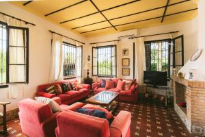 a living room with red couches and a tv at Villa La Jara Sanlúcar in Sanlúcar de Barrameda