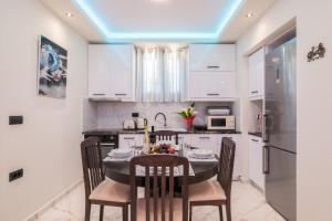 una cucina con mobili bianchi e un tavolo con sedie di Alkeos Suite by "elite" a Città di Zante Altre 13 foto