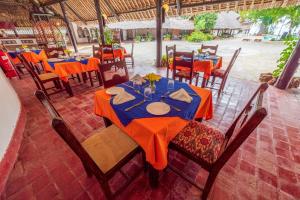 ein Restaurant mit Tischen und Stühlen mit orangefarbenem Tischtuch in der Unterkunft Safari Beach Hotel in Diani Beach