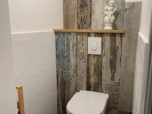 a bathroom with a white toilet and a wooden wall at Les Clématites, maison de campagne. in Boissy-lès-Perche