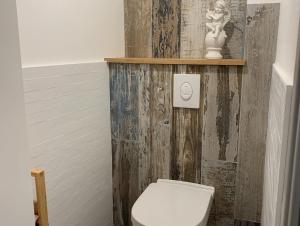 a bathroom with a white toilet and a wooden wall at Les Clématites, maison de campagne. in Boissy-lès-Perche +11 photos