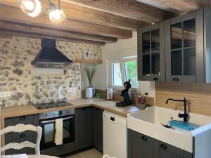 a kitchen with a sink and a stove top oven at Les Clématites, maison de campagne. in Boissy-lès-Perche