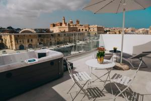 einen Balkon mit einer Badewanne, einem Tisch und Stühlen in der Unterkunft Dock 1 Boutique Hotel in Cospicua