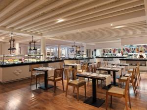 a restaurant with tables and chairs and a kitchen at H10 Ocean Suites in Corralejo