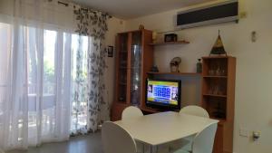 a dining room with a white table and a television at Bonito apartamento, con piscina, excelente wifi y aire acondicionado in Pals