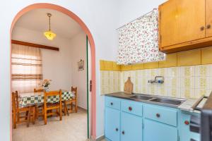 a kitchen with blue cabinets and a dining room with a table at Alexandros Studios by Estia in Benitses