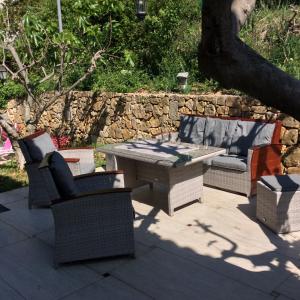 un patio con tavolo e sedie e un muro di pietra di bienvenue chez Alain et Marie a Antibes