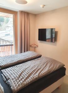 a bedroom with a bed and a television on the wall at Ferienwohnung Stenna SELVA an Toplage in Flims