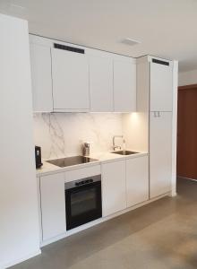 a white kitchen with white cabinets and a sink at Ferienwohnung Stenna SELVA an Toplage in Flims