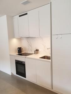 a kitchen with white cabinets and a sink at Ferienwohnung Stenna SELVA an Toplage in Flims
