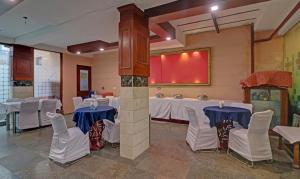 a banquet hall with white tables and white chairs at Itsy By Treebo - Hamlets Stay in Noida