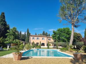 une villa avec une piscine en face d'une maison dans l'établissement Le Clos des Cyprès Maison d'hôtes de charme & Diner Gourmet, à Graveson