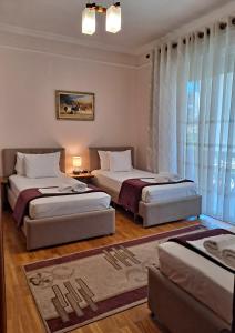 1 dormitorio con 2 camas y ventana en All Seasons Apartments, en Shkodër