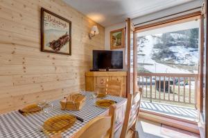 a dining room with a table and a tv and a balcony at La Loutre in La Giettaz