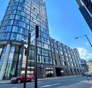 um carro vermelho está estacionado em frente a um grande edifício em Sheffield City Centre Studio em Sheffield