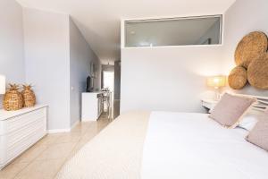 a white bedroom with a large bed and a kitchen at Apartamentos Barranco del Infierno in Adeje