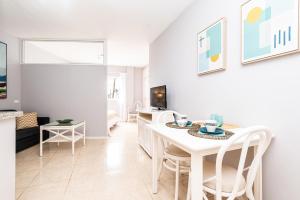 una sala de estar blanca con mesa y sillas en Apartamentos Barranco del Infierno, en Adeje