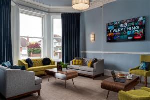 a living room with couches and chairs and a tv at St Andrews Hotel in Exeter