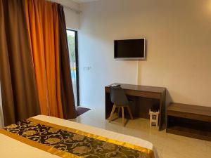 a hotel room with a desk and a television at Welcome Inn in Grand Baie