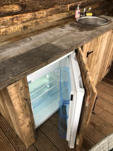 an open refrigerator under a counter with a sink at Gracelands Glamping lodge 1 in Ballyronan