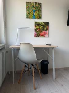 a desk with a chair and two paintings on the wall at The HIKER City Apartment in Koblenz