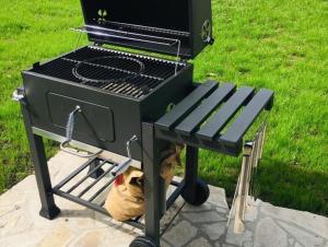a barbecue grill with a bench next to a field at Вила Вълнара in Sredets