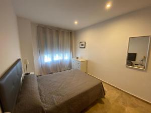 Apartamento Tía Maria في كاديز: غرفة نوم صغيرة مع سرير ومرآة