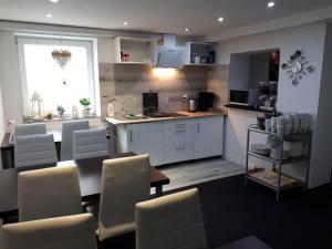 a kitchen with white chairs and a table and a counter at 4 Pory Roku in Karpacz