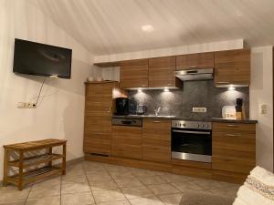a kitchen with wooden cabinets and a tv on the wall at Sepps Appartement in Fieberbrunn