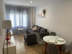Apartamento Tía Maria في كاديز: غرفة معيشة مع أريكة وطاولة مع كراسي