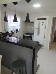 cocina con encimera negra y nevera blanca en Casa aconchegante com lareira en Campos do Jordão