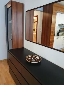 a black dresser with a mirror and a plate on it at Apartament Cafe Del Mar in Świnoujście
