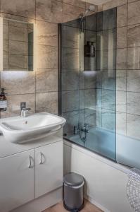 a bathroom with a sink and a glass shower at Modern 3-Bed House on Tarporley High Street in Tarporley