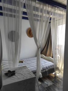a bedroom with white curtains and a bed with a box at Malli Sea House in Mamádhos