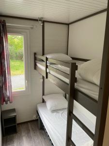 two bunk beds in a small room with a window at Village Vacances Chateau de Tréambert in Mesquer