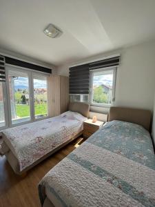 twee bedden in een slaapkamer met twee ramen bij Oasis Royal Apartments in Sarajevo