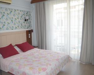 a bedroom with a bed with red pillows and a window at Akman Hotel in Kuşadası