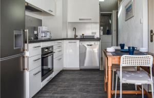 1 Bedroom Lovely Apartment In Noirmoutier-en-lle في نوارموتيير أون ليل: مطبخ بأدوات بيضاء وطاولة خشبية