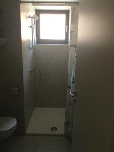 uma casa de banho com um chuveiro, uma janela e um WC. em Lovely studio appartment with patio near the sea em Koper