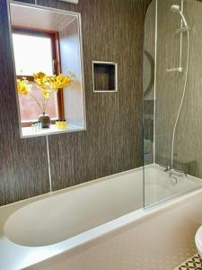 a bathroom with a tub and a sink and a mirror at The Smiddy in Inverness