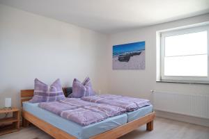 una camera da letto con un letto con cuscini viola e una finestra di Ferienwohnung-MAJA-in-Sassnitz-fuer-2-Erwachsene-und-1-Kind-oder-3-Erwachsene a Sassnitz