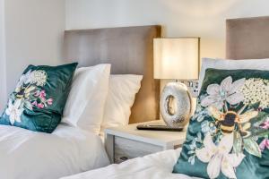 a bedroom with two beds with pillows and a table with a lamp at The Butler Suite in York