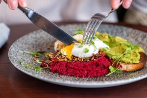 una persona che tiene in mano un coltello, una forchetta e un piatto di cibo di The St George and Dragon by Innkeeper's Collection a Topsham