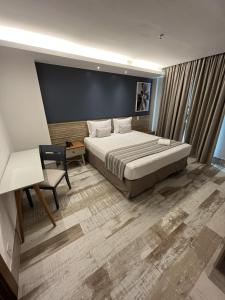 1 dormitorio con cama, escritorio y silla en Golden Towers Hotel, en Macaé