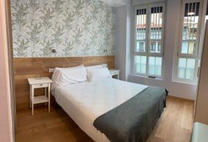 sypialnia z łóżkiem, stołem i dwoma oknami w obiekcie Aloha Hostel w Pampelunie